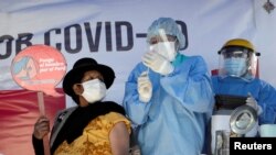 Peruanka, koja drži natpis "Stavio sam rame za Peru", prima vakcinu AstraZeneca protiv COVID-19, na Međunarodnom mostu u Desaguadero, između Bolivije i Perua 21. maja 2021. 