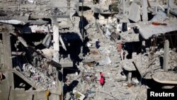 Disa fëmijë palestinezë duke ecur në gërmadha në qytetin Han Junis, në Gazë.