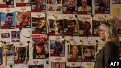 Žena prolazi pored zida na kojem su prikazani portreti izraelskih talaca koji su zarobljeni u Gazi od napada Hamasa 7. oktobra, Tel Aviv, 28. 12. 2023.