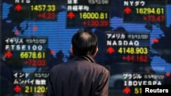 Жолоочу адам баалуу кагаздардын рыногундагы акциялардын сатылышын көрсөткөн электротаблону карап турат. Токио. Декабарь 2013