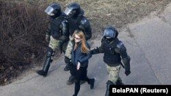 A woman is led away by Belarusian police after they broke up a rally in Minsk on March 27.