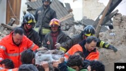 Італійські рятувальники виносять пораненого з під завалів в місті Аквіла