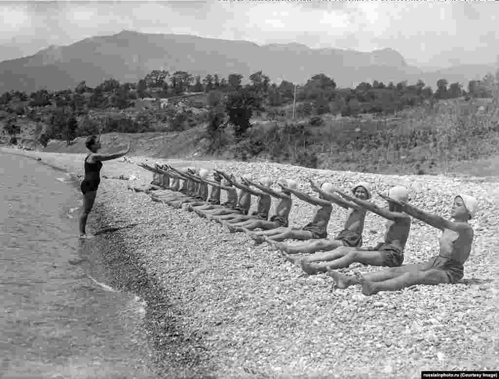 Вправи на гальковому пляжі в «Артеку» в 1930-х роках. Невдовзі табір розширився і став частиною комуністичної молодіжної організації Радянського Союзу – піонерської організації. Щоліта в «Артеку» виділяли місця для дітей з високим рівнем успішності, а також для дітей членів комуністичної партії з хорошими зв'язками