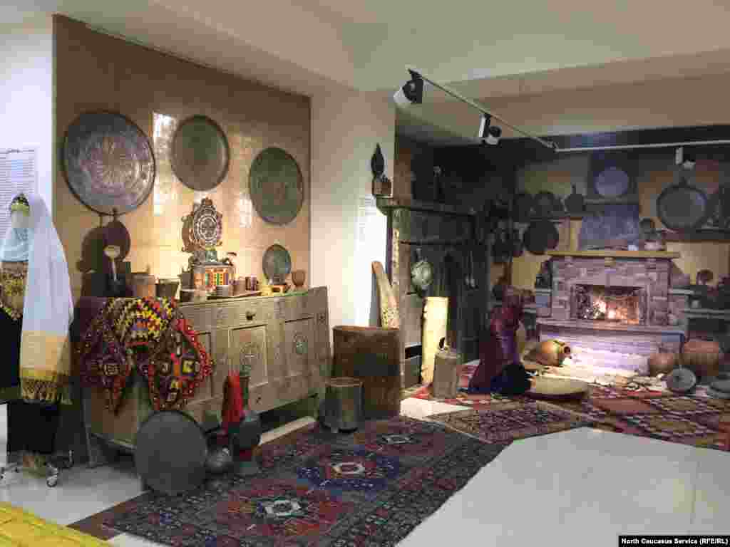 Именно так и выглядела изнутри горская сакля. На переднем плане &ndash; водоносные кувшины, деревянные мерки для зерна, сандук для хранения муки. В разноцветном приборе на сандуке держали ложки, вилки, ножи. В медные блюда (висят на стенах) клали еду для всей семьи. Слева на сандуке свисает хулжал (своеобразная сумка горцев), а поодаль &ndash; камин (по-аварски &quot;гъасито&quot;) 