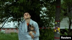 A Kyiv resident surveys the damage to an apartment building hit during a Russian overnight drone strike on the Ukrainian capital on May 24. 