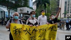 A hongkongi demokráciapárti ellenzék néhány tagja egy bíróságnál tüntet a politikai foglyok kiszabadításáért, 2021. május 17-én
