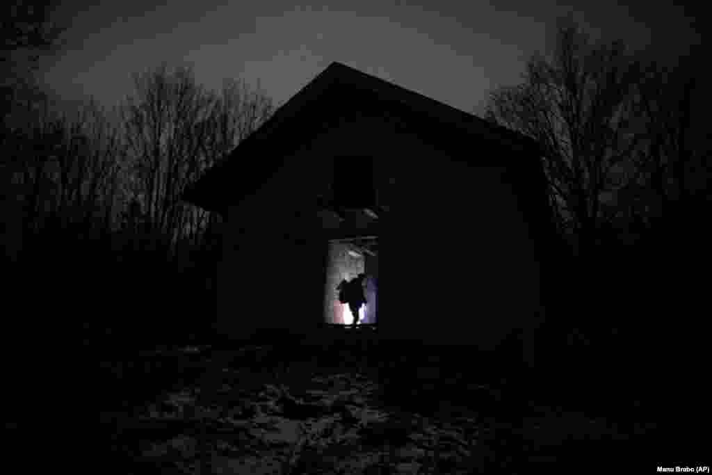 Një migrant qëndron në derën e një ndërtese, para se grupi të cilit i takon, të vazhdojnë rrugëtimin e tyre në perpjekje për të kaluar në territorin kroat.&nbsp;