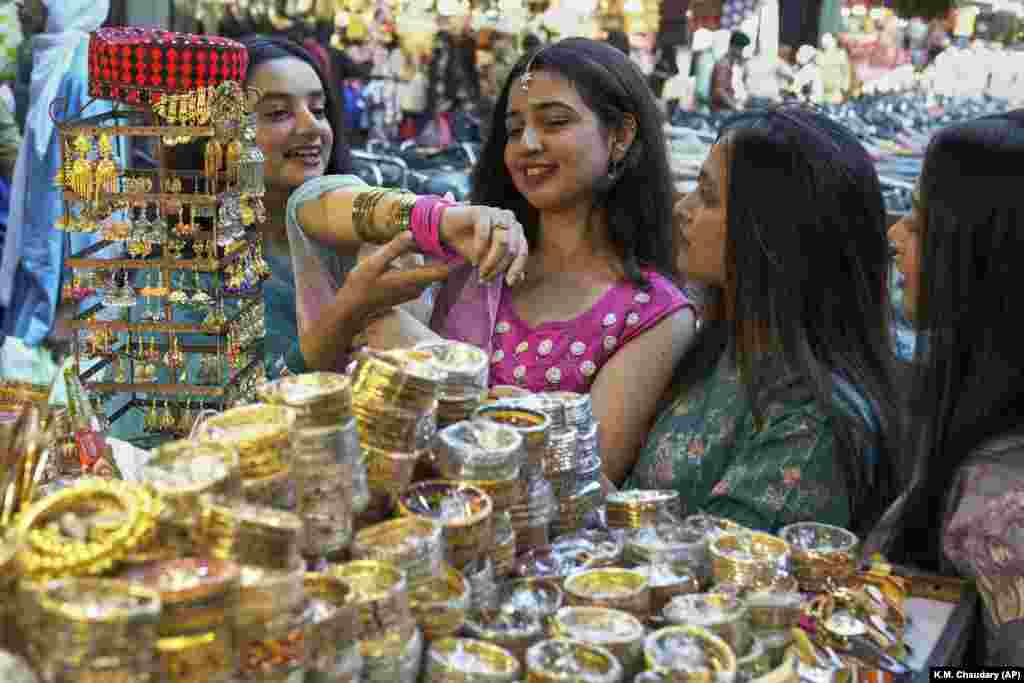دخترانی در لاهور پاکستان در حال تماشای النگوها و زیورآلات سنتی در بازار، در آستانهٔ عید فطر.