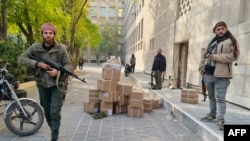 Combatanți antiguvernamentali, păzind cutii cu bani după prevenirea unor jafuri la banca centrală din Damasc, pe 8 decembrie 2024.