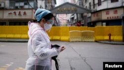 Një grua me veshje mbrojtëse kundër COVID-19 duke ecur në një rrugë në Vuhan - Fotografi ilustruese nga arkivi. 