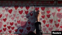 Londra, Zidul în Memoria celor morți de Covid - o femeie mai adaugă un nume după ce duminică s-au anunțat noi restricții sanitare în Marea Britanie legate de tulpina Omicon, 28 noiembrie 2021. 