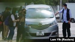 HONG KONG -- Apple Daily’s Deputy Chief Editor Chan Pui-man is escorted by police into the offices of Apple Daily and Next Media after police arrested five Apple Daily executives in Hong Kong, China June 17, 2021. REUTERS/Lam Yik