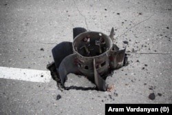 Aripile cozii unei rachete mari, înfipte în asfalt pe o stradă din Stepanakert
