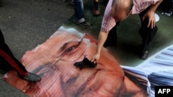 Demonstrant stavlja svoju cipelu na lik Ahmada Šafika