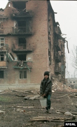 Хлопчик несе воду у підвал, де переховуються його рідні, у повністю зруйнованому російськими обстрілами і бомбардуванням Грозному. Чечня, 14 лютого 2022 року