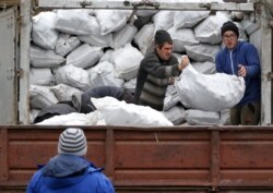 Жителям поселка помогают благотворительные организации. Разгрузка топливных брикетов от «Каритас-Мариуполь»