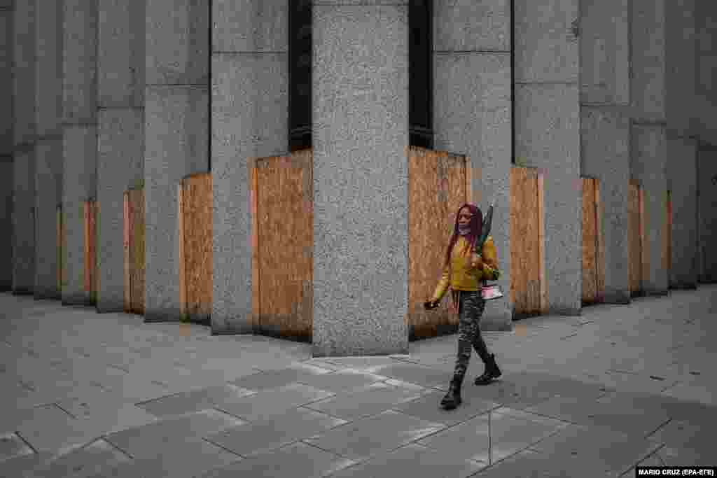 Жена поминува низ продавница заштитена со дрвени табли во Вашингтон.