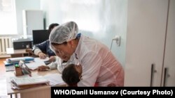 Кызамыкка каршы эмдөө кампаниясы учурунда вакцига алган бала дарыгерди кучактап турат. ДСУ/Данил Усманов