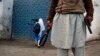 A man with a gun and a metal detector poses for photographers while he stands outside a school in Peshawar.