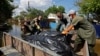 Voluntari și lucrători municipali scot saci cu cadavre din casele inundate, după ce apele s-au retras în urma distrugerii barajului Nova Kakhovka, în orașul Hola Pristan din regiunea Herson, Ucraina controlată de Rusia, 16 iunie 2023.