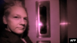 Julian Assange osnivač Wikileaksa se vidi kroz teško zatamnjen prozor policijskog vozila na putu do Vestminsterskog prekršajnog suda u Londonu, 14. decembar 2010.