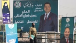 O femeie trece pe lângă afișe electorale înaintea alegerilor parlamentare din Irak, desfășurate în Sadr City, la est de Bagdad 