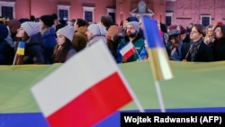 Люди слухають звернення президентів Польщі та України у дворі Королівського замку у Варшаві. Польща, 5 квітня 2023 року