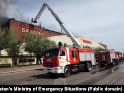 Астанадағы "Шапағат" базарындағы өртті сөндіруге барған арнайы қызмет өкілдері мен көліктері. Қазақстанның Төтенше жағдайлар министрлігі жариялаған фото. 8 мамыр, 2025 жыл.