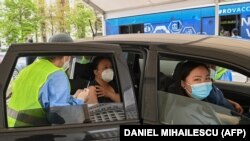 Az embereket Pfizer–BioNTech-vakcinával oltják be egy újonnan megnyílt autós oltóközpontban Bukarestben, 2021. április 29-én