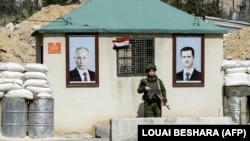 Російьский військовий між портретами Володимира Путіна (л) і Башара Асада (п) на КПП на околиці Дамаска, 1 березня 2018 року