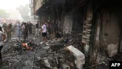 Iraqis inspect the damage at the site of a suicide car bombing claimed by the Islamic State group on July 3, 2016 in Baghdad's central Karrada district. The blast, which ripped through a street in the Karrada area where many people go to shop ahead of the