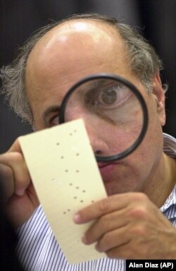 Egy választási tisztségviselő nagyítóval vizsgál egy vitás szavazócédulát a Broward megyei bíróságon Ford Lauderdaleben, Floridában, 2009. november 24-én.