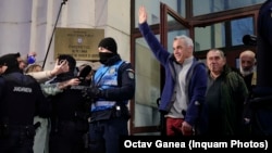 Călin Georgescu salută mulțimea la ieșirea din Parchetul General. Fostul candidat extremist a fost pus sub control judiciar.