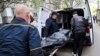 Ukrainian municipal workers move a dead body into a car near a multistory building damaged by a Russian strike on a residential neighborhood in Zaporizhzhya on April 22.