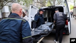 Ukrainian municipal workers move a dead body into a car near a multistory building damaged by a Russian strike on a residential neighborhood in Zaporizhzhya on April 22.