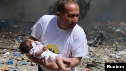 مرد سوری کودکی را از خرابه‌های بمب‌های بشکه‌ای نیروهای دولتی بیرون می‌برد