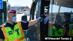 Egy belépő gépjármű utasainak hőmérsékletét ellenőrzi egy rendőr a hegyeshalmi határátkelőnél 2020. szeptember 5-én.