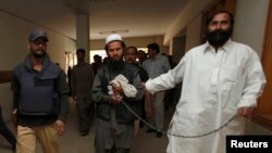 Pakistani Police escort a man through the halls of a court in Karachi.