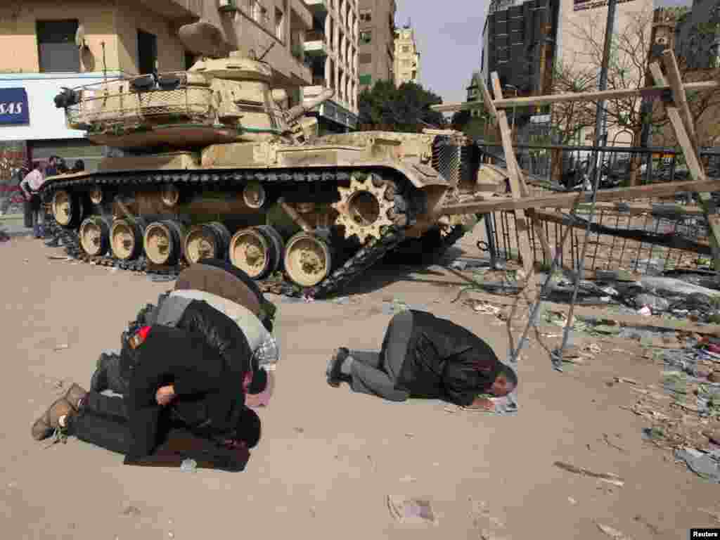 Opposition supporters pray next to a tank on Tahrir Square.