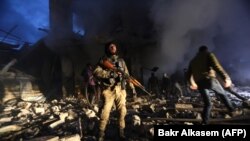 A szíriai civil önvédelmi szervek és a törökök által támogatott szíriai erők túlélők után kutatnak Azaz városában, egy autóba rejtett pokolgép robbanása után, 2020. március 19-én.