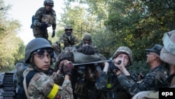 Українські військові несуть пораненого під час бою поблизу міста Іловайська, 10 серпня 2014 року 