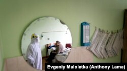 Egy különleges védőöltözetet viselő orvos egy pácienssel beszél az ukrajnai Sztrij városi kórházában 2020. szeptember 29-én