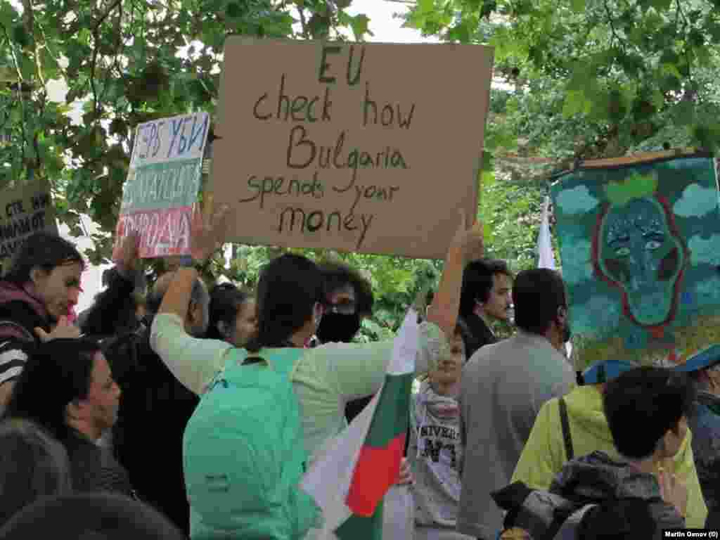 Протестираща с плакат, призоваващ: &quot;ЕС, провери как България харчи парите ти&quot;.