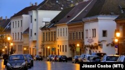 A budai Vár Tárnok utcájának díszes régi épületei és az előttük parkoló autók a kora esti fényben