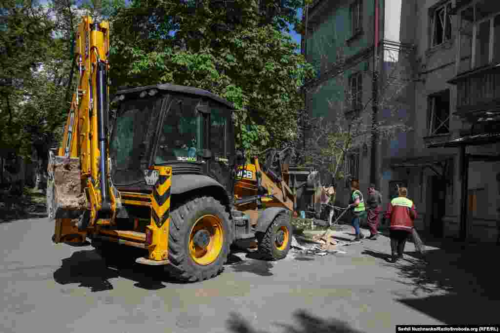 Комунальні служби прибирають уламки, бите скло від пошкодженого будинку 