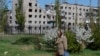 A woman walks in front of an apartment building damaged in the course of Russia-Ukraine war. (file photo)
