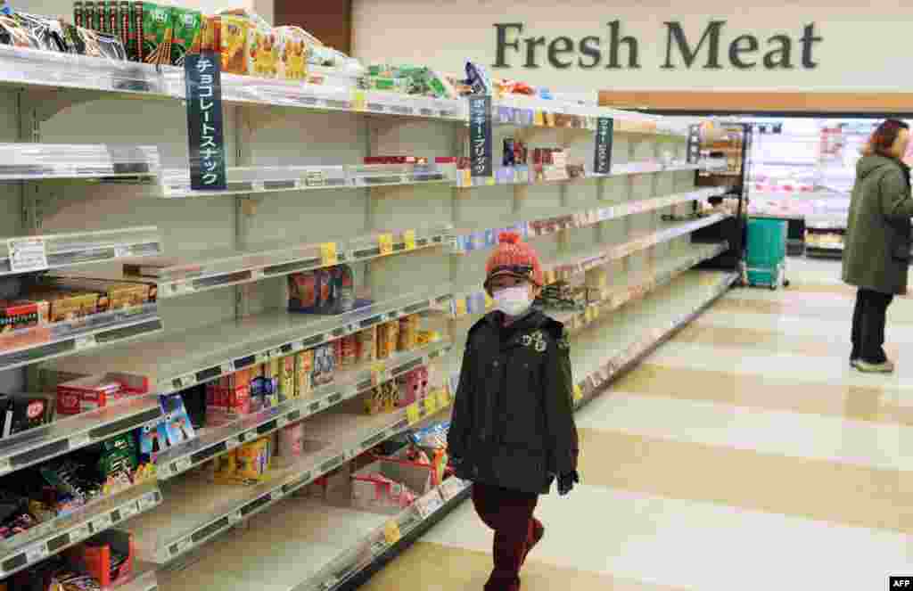 Një djalë me maskë ecën nëpër një dyqan ushqimesh në Akita më 15 mars, 2011. Banorët e këtij qyteti pothuajse boshatisën dyqanet ushqimore, pas tërmetit dhe cunamit si dhe krizës në Fukushima. Kriza bërthamore në Japoni u përshkallëzua më 15 mars, pas dy shpërthimeve në centralin bërthamor, duke bërë që nivelet e rrezatimit të arrinin në nivele të rrezikshme.&nbsp; &nbsp;