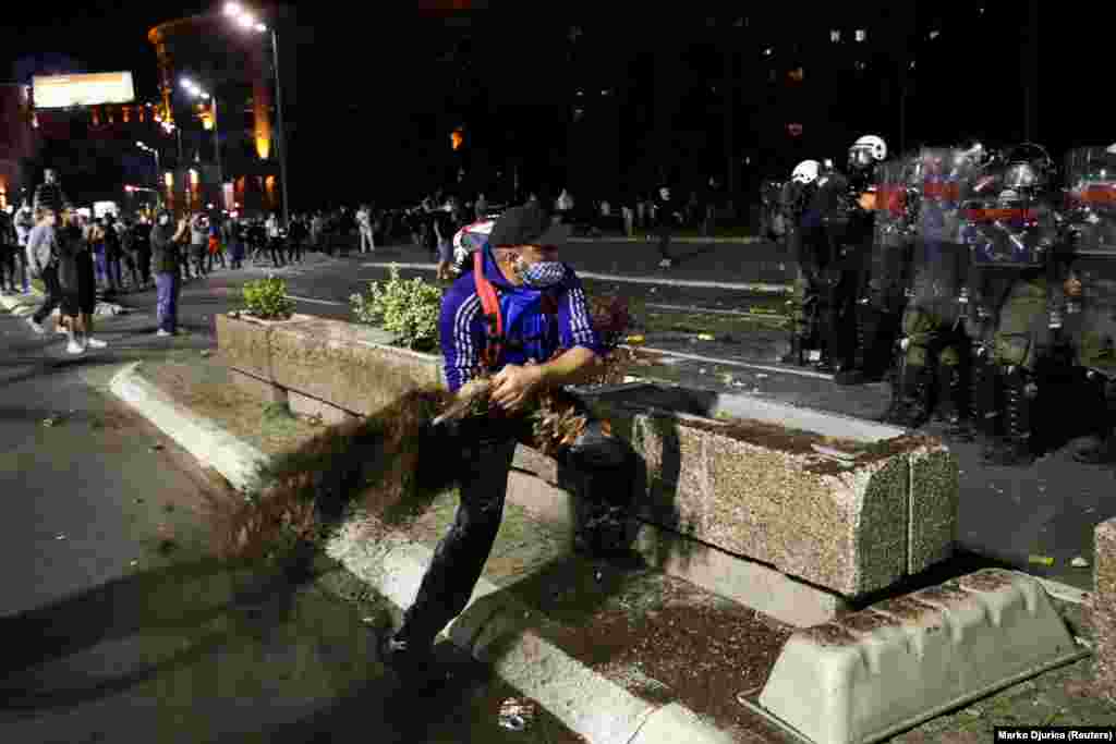 На фото: чоловік замахується на представників поліції вирваним кущем.