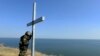 A Ukrainian serviceman prays by a cross outside the eastern city of Mariupol, a port of crucial economic importance on the Azov Sea.