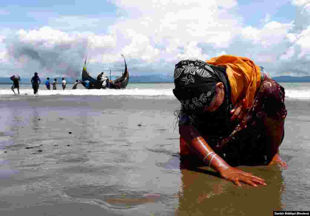 An exhausted Rohingya refugee woman touches the shore after crossing the Bangladesh-Myanmar border by boat through the Bay of Bengal in Shah Porir Dwip, Bangladesh, September 11, 2017. (Reuters/Danish Siddiqui)